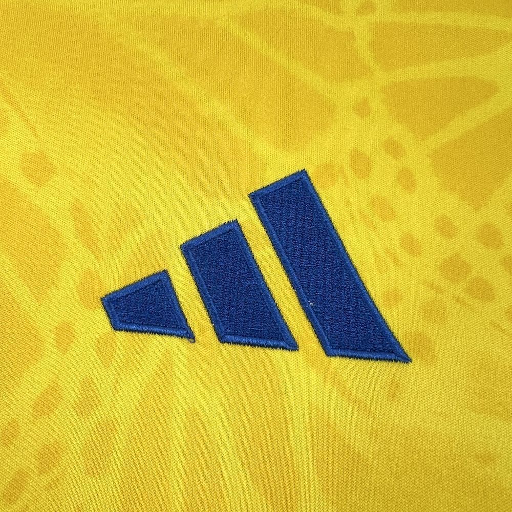 Blue Adidas logo on yellow soccer jersey fabric.