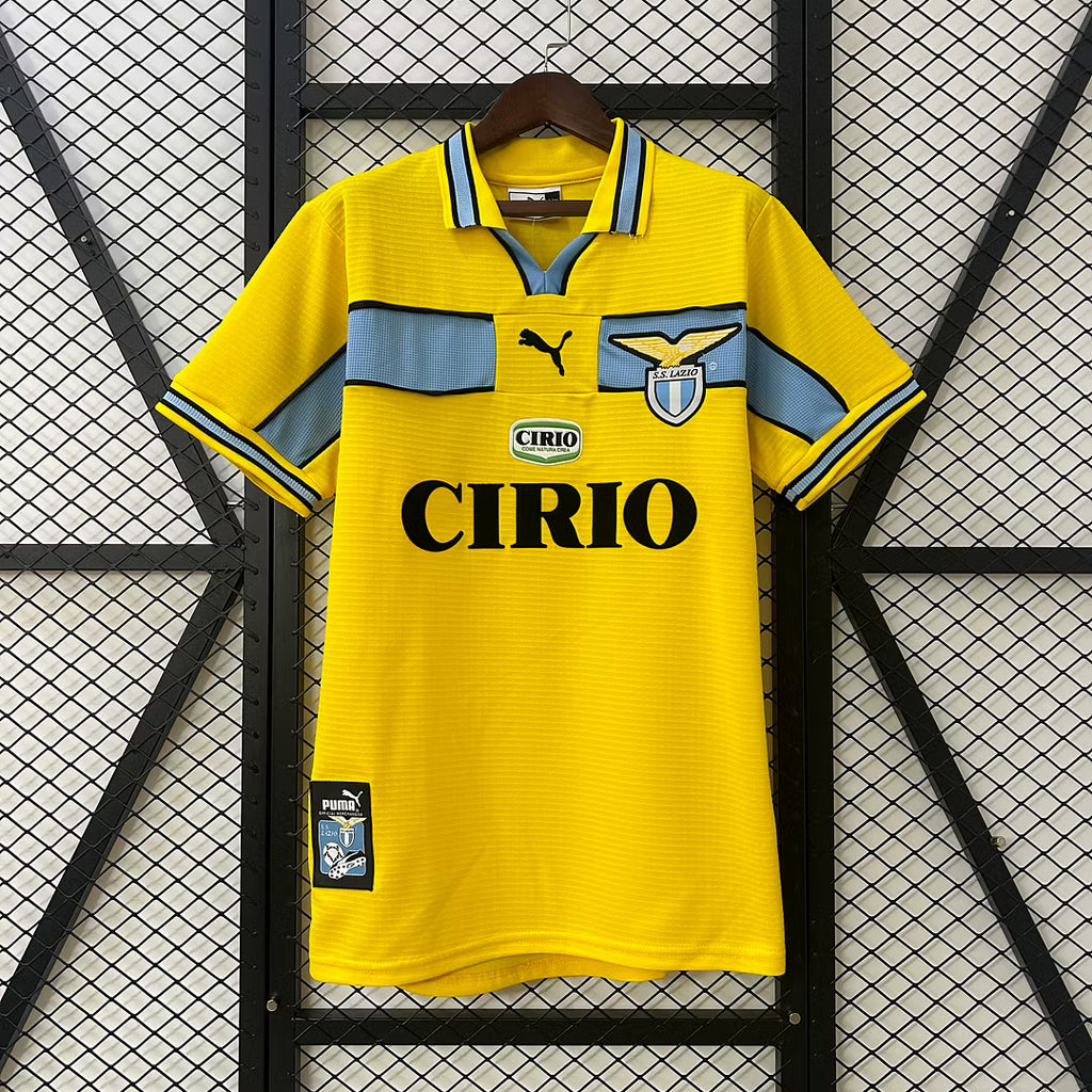 Yellow retro soccer jersey with light blue stripes, PUMA logo, Lazio crest, CIRIO sponsor