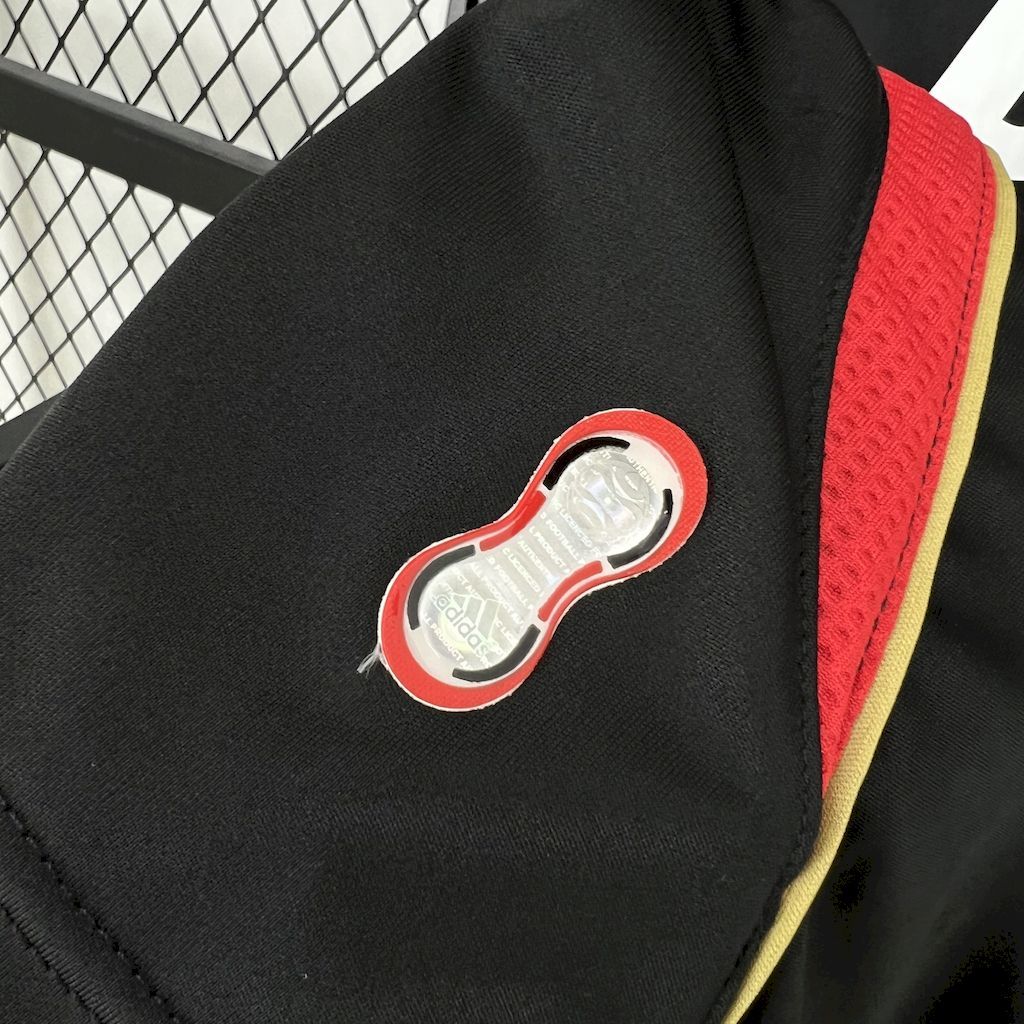Black jersey sleeve with embroidered red-and-white shell logo and yellow-red trim edge