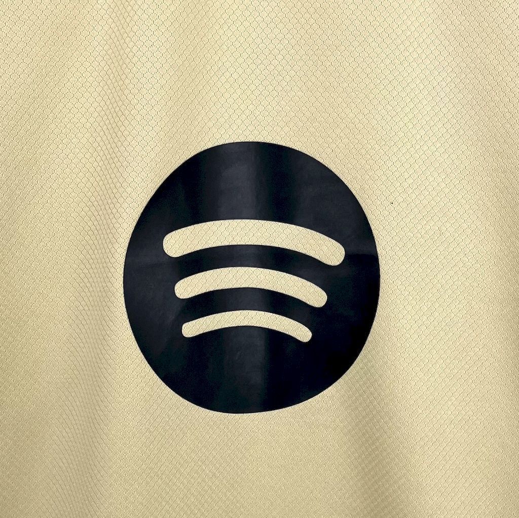 Light yellow FC Barcelona jersey front, dark circular logo with three beige lines