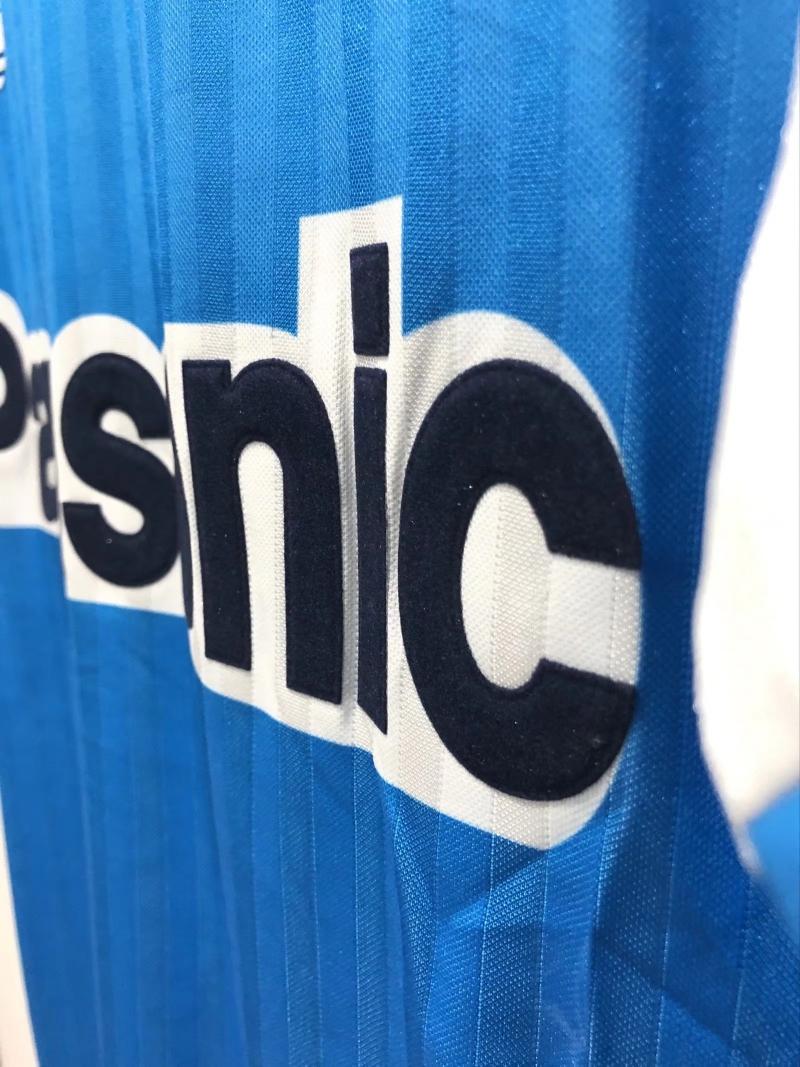 Panasonic sponsor print detail on blue textured retro soccer jersey