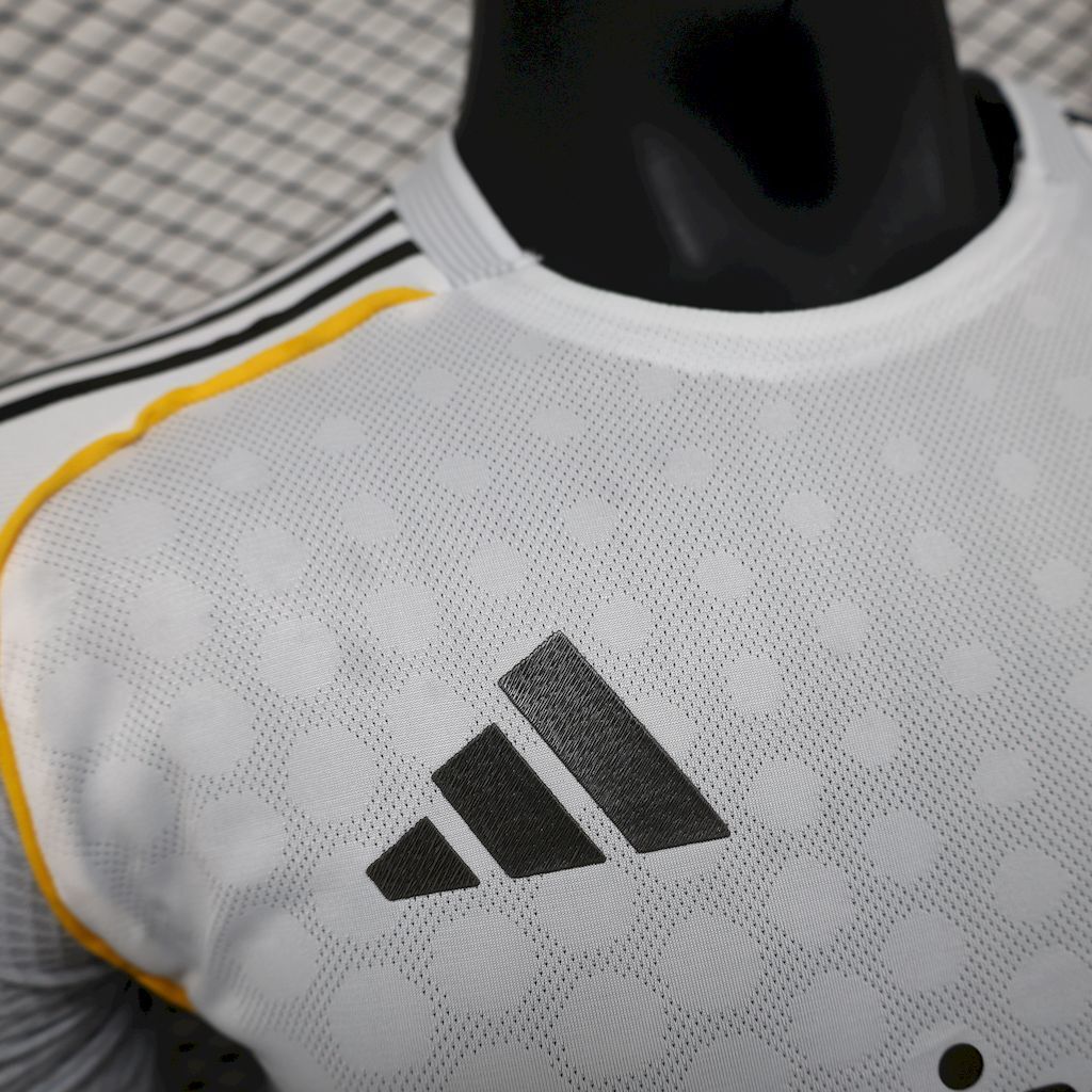 White jersey close-up of textured pattern and adidas logo, yellow seam piping