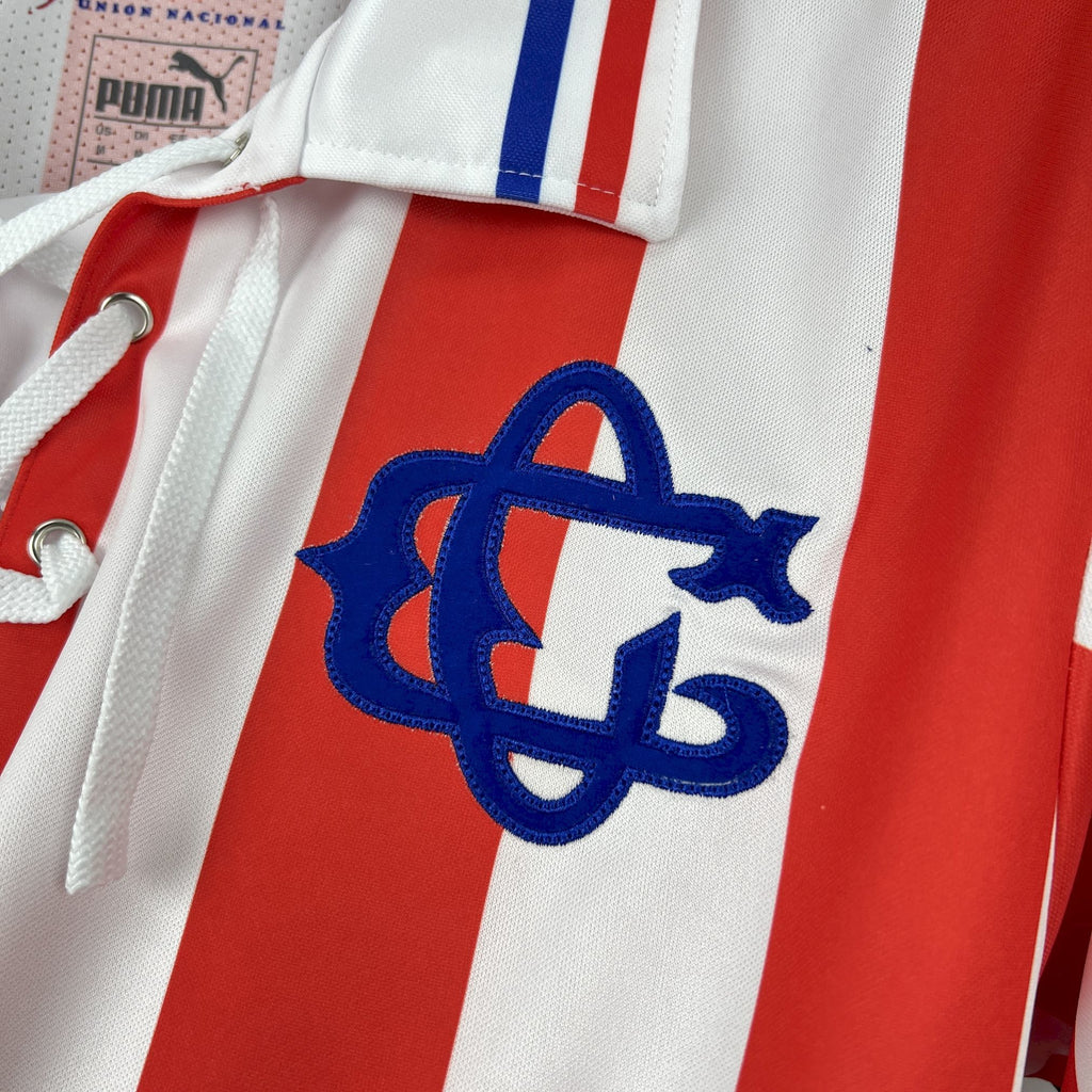 Retro soccer jersey front close-up with large blue interlocking emblem on striped fabric.