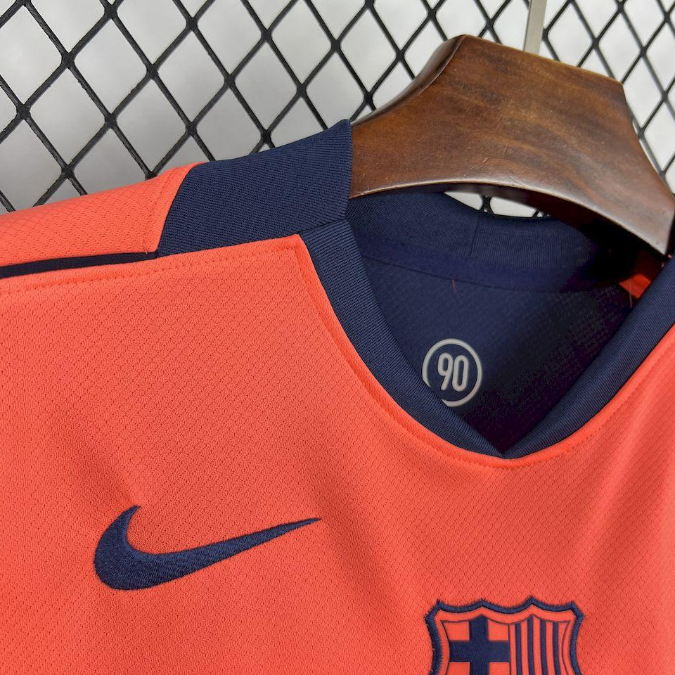 Orange football jersey with navy V-neck, Nike swoosh, and FC Barcelona crest