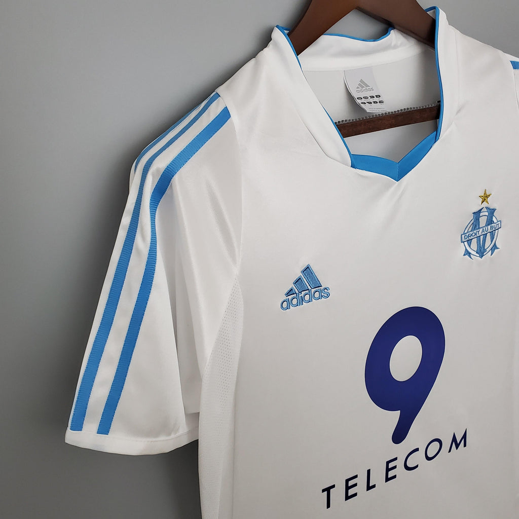 White football jersey close-up with adidas logo, blue stripes, and number 9
