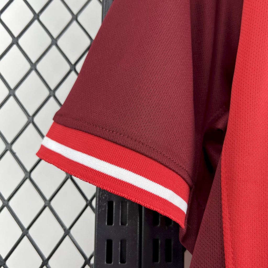 Red soccer jersey sleeve cuff with bold white stripe and stitched edge seam.