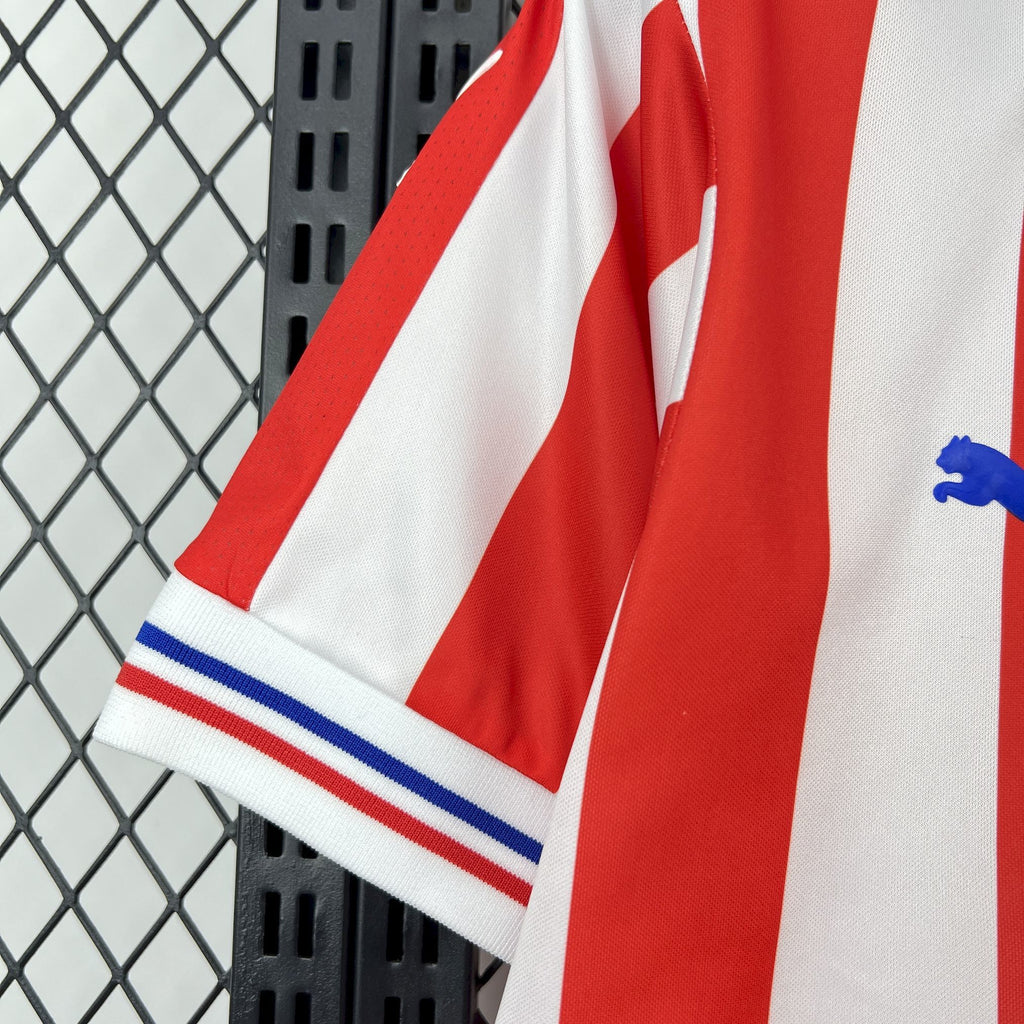 Retro soccer jersey sleeve end with blue-and-white ribbed cuff and red-and-white stripes.