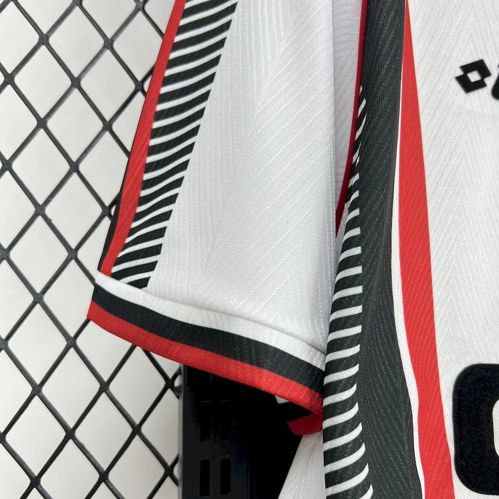 Side close-up of jersey hem with red piping and black-and-white striped panel