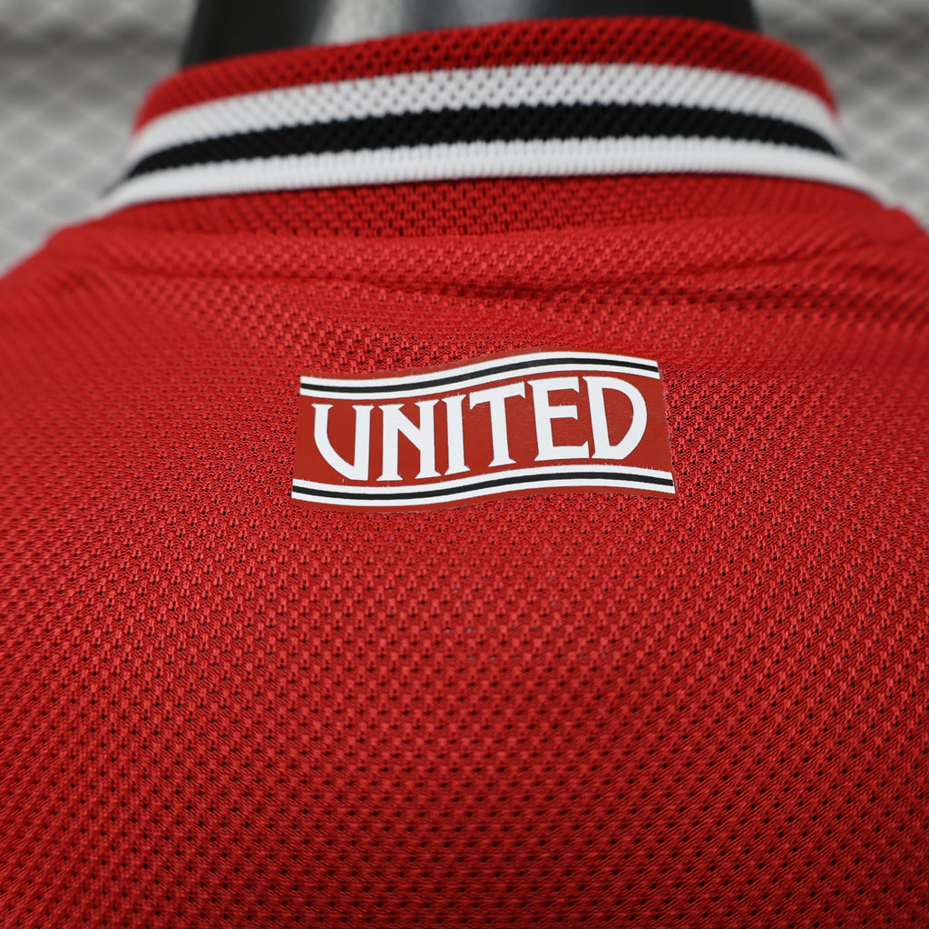 Red jersey close-up of UNITED badge with white border