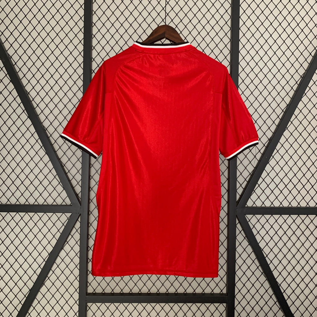 Red home football shirt with V-neck trim and short sleeves, back view
