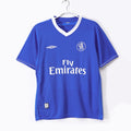 Blue football jersey with white V-neck trim, Fly Emirates sponsor and club crest