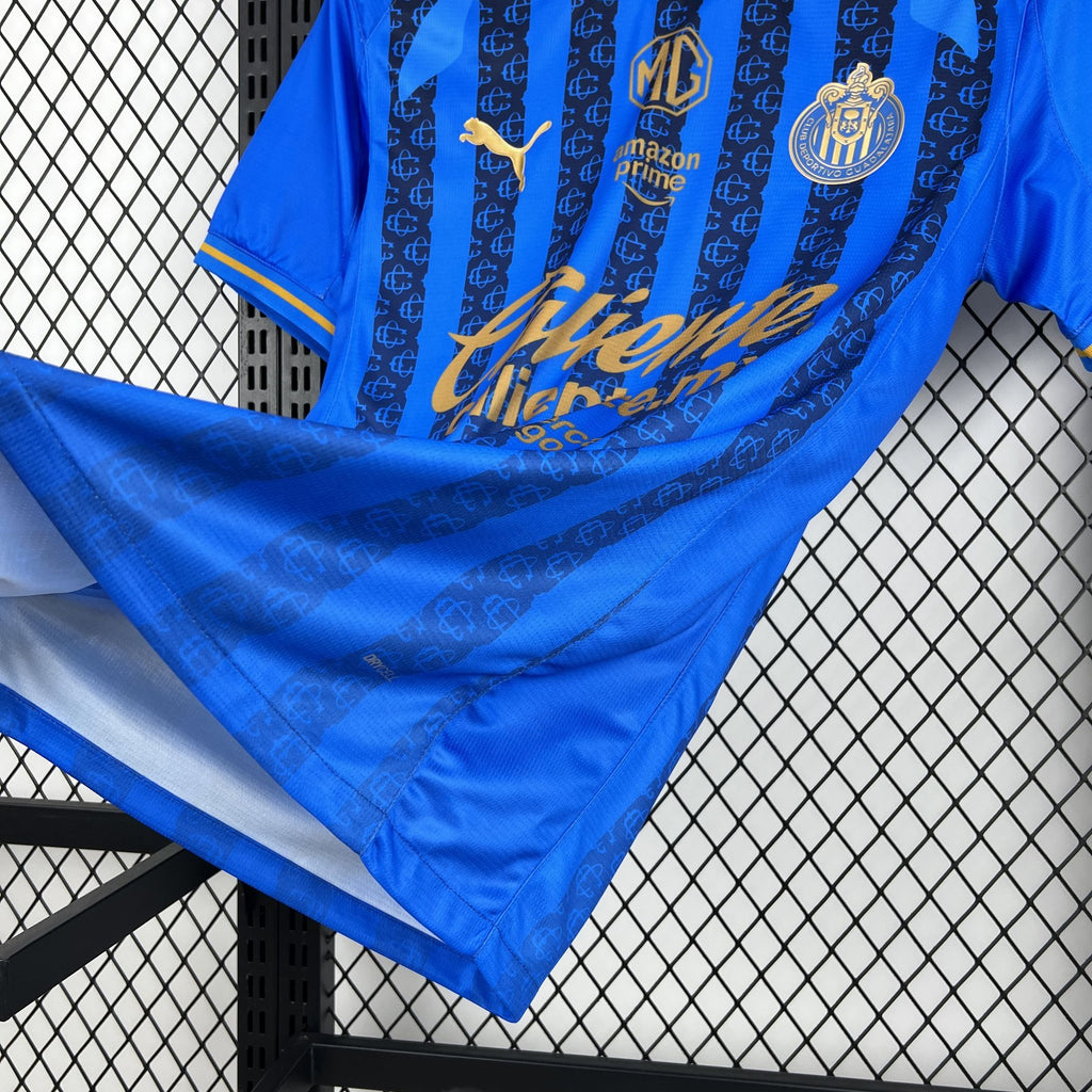 Blue soccer jersey fabric close-up with vertical stripes and gold script print; folded