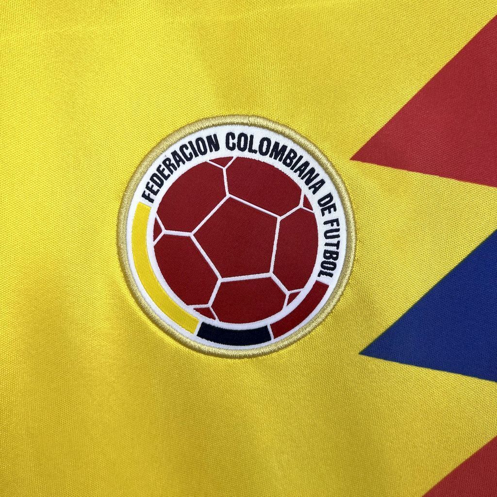 Round soccer federation crest patch on yellow jersey with red and blue accents