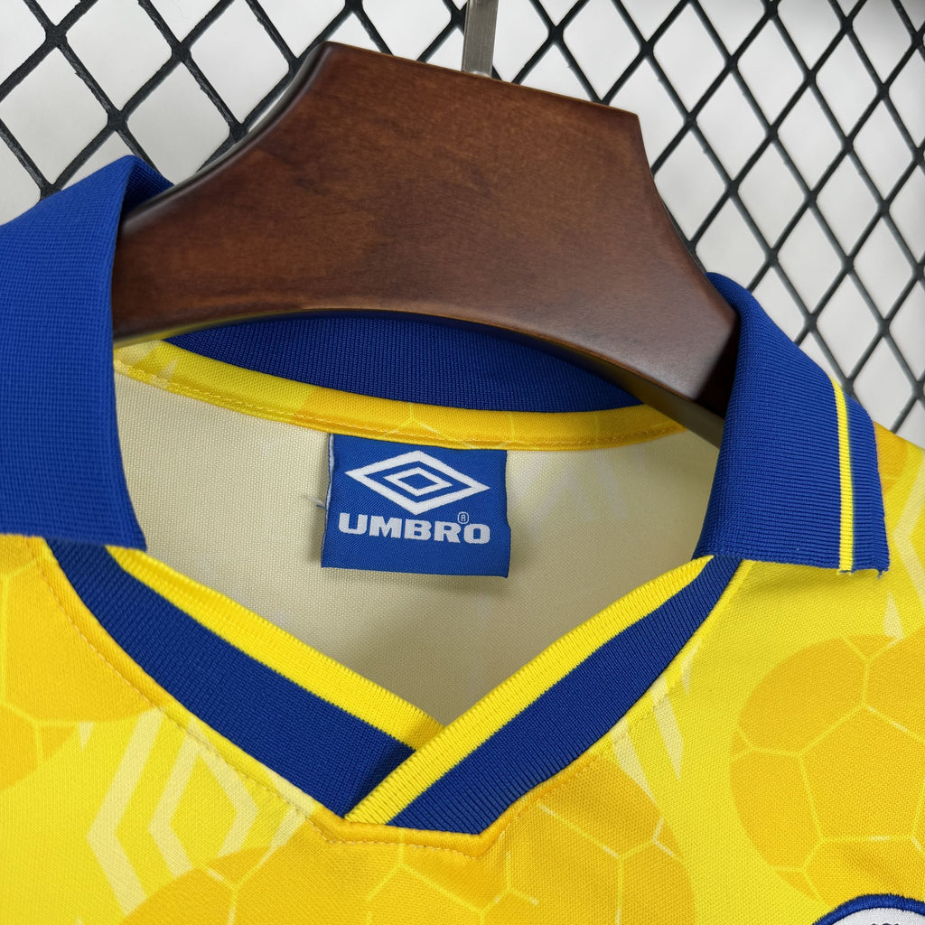 Yellow soccer jersey neckline with blue V trim and Umbro brand tag.