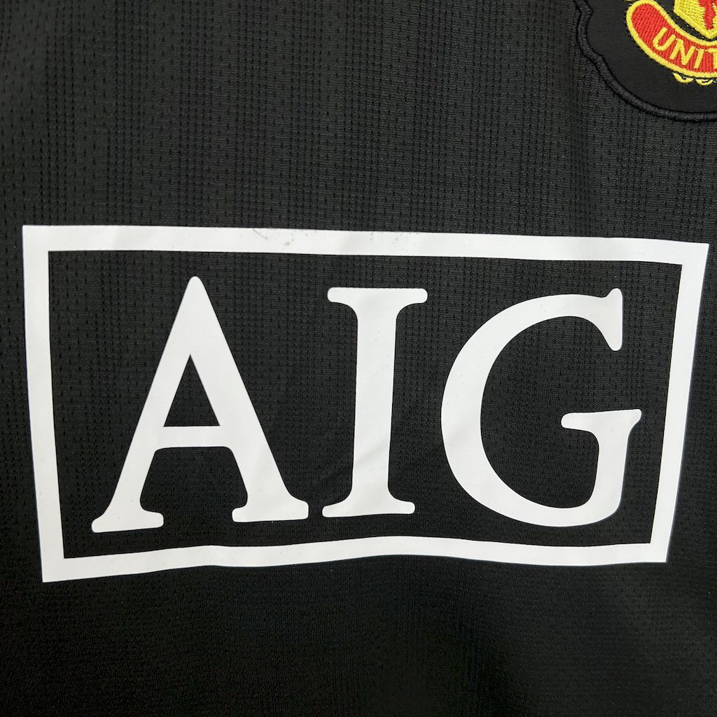Retro away football jersey close-up of white AIG sponsor on black shirt