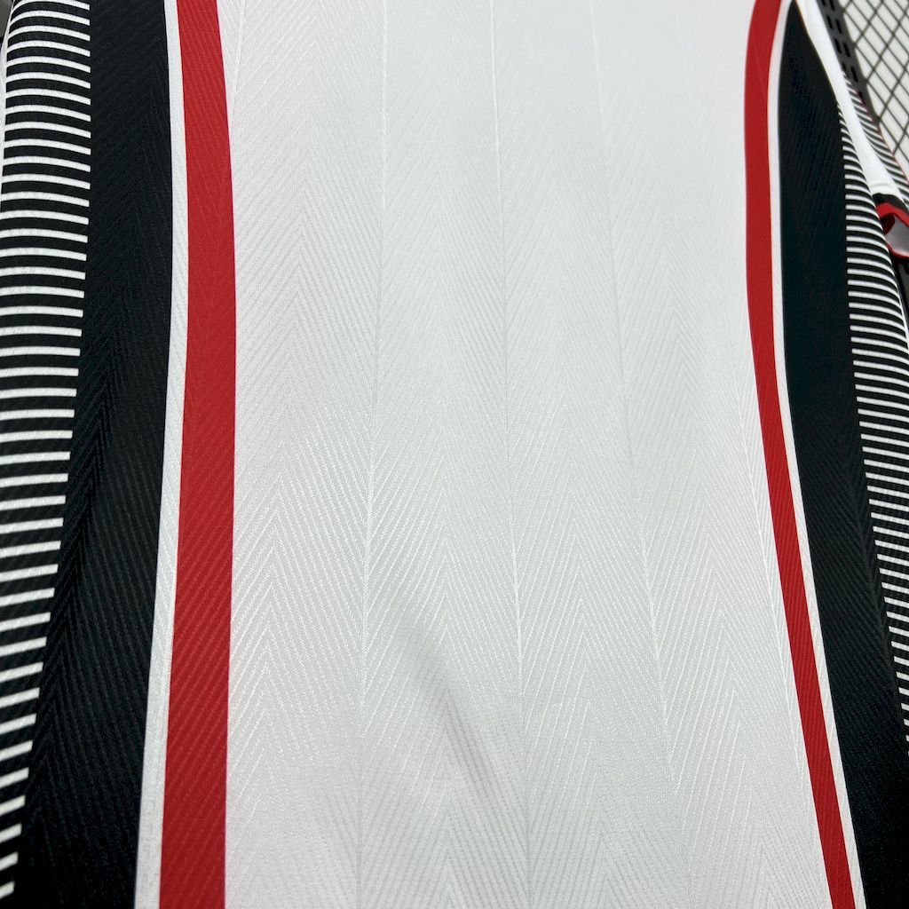 Close-up of white jersey front panel with red vertical trim and black striped edge