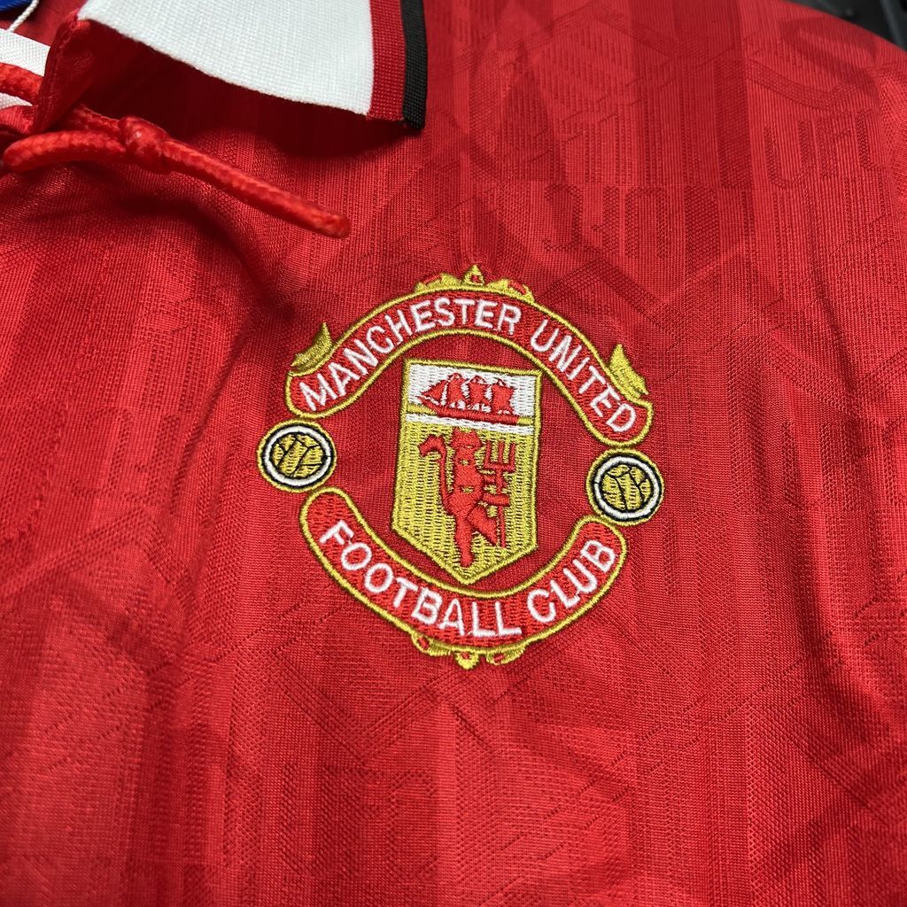 Embroidered Manchester United Football Club crest patch on red jersey fabric