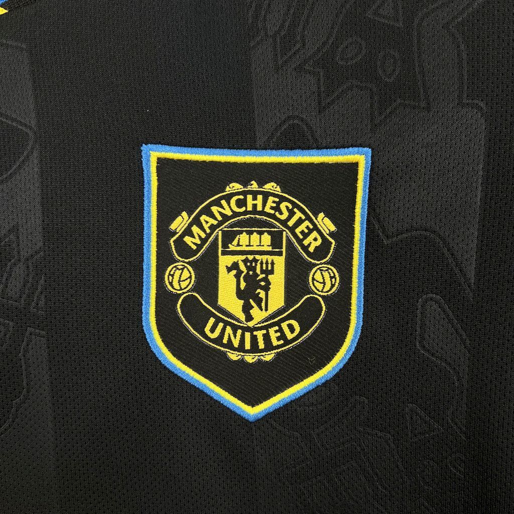 Women's third jersey chest crest, Manchester United badge in yellow and blue outline.