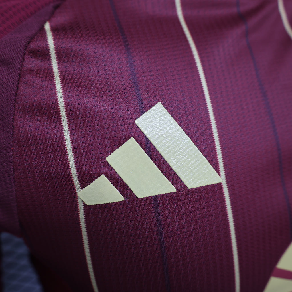 Close-up of three gold adidas stripes on maroon jersey