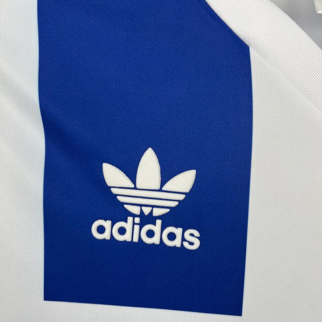 Close-up adidas trefoil logo on the blue panel of a blue and white striped retro jersey