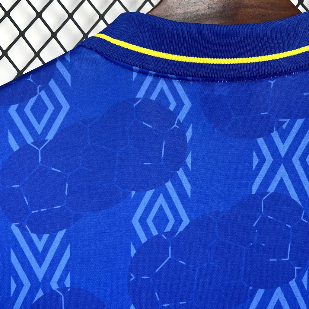 Blue jersey fabric close-up with hexagon and geometric graphics, yellow collar trim