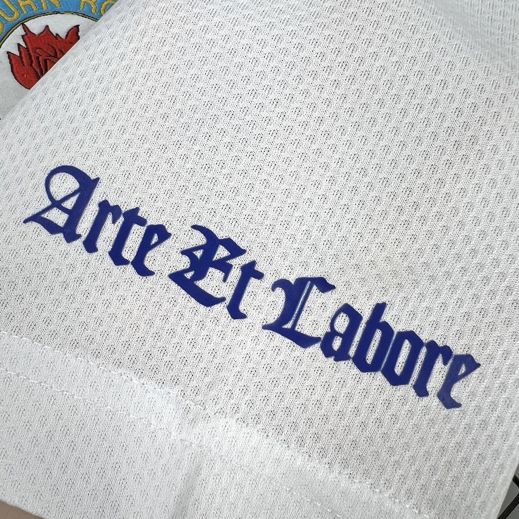 Close-up of retro football shirt neckline with “Arte et Labore” embroidery in blue