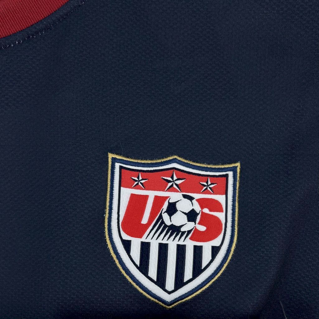 USA shield crest on navy soccer jersey, black-and-white ball graphic.