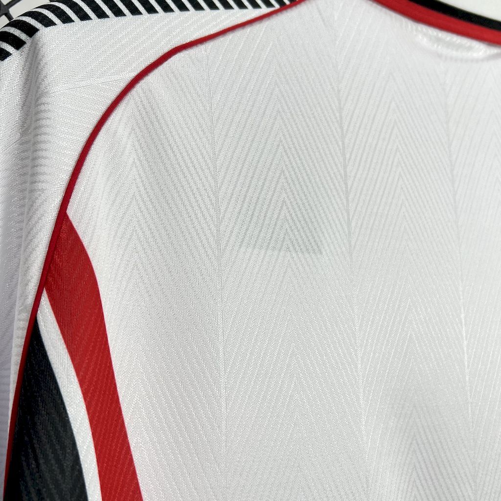 White soccer jersey fabric close-up with red seam piping and black-and-white shoulder stripes