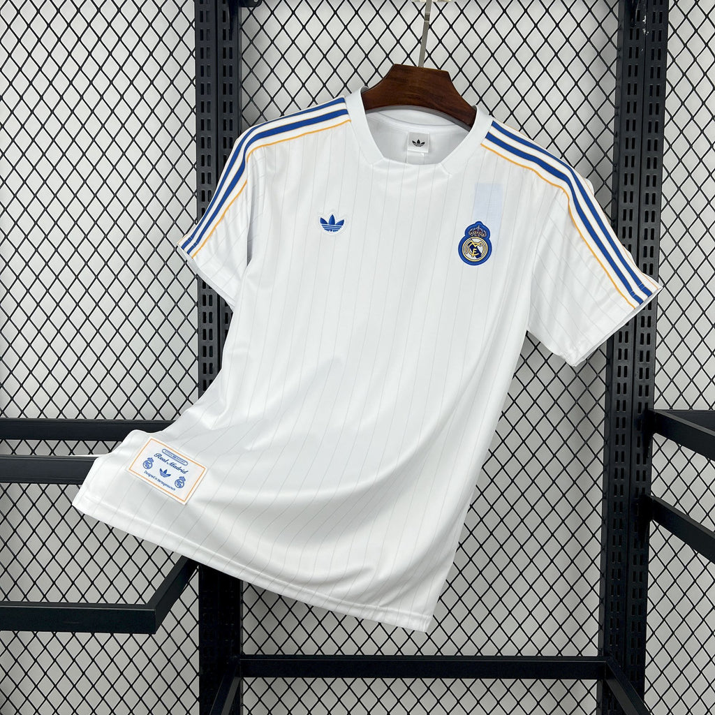 White Real Madrid football jersey with blue-and-gold shoulder stripes and badge