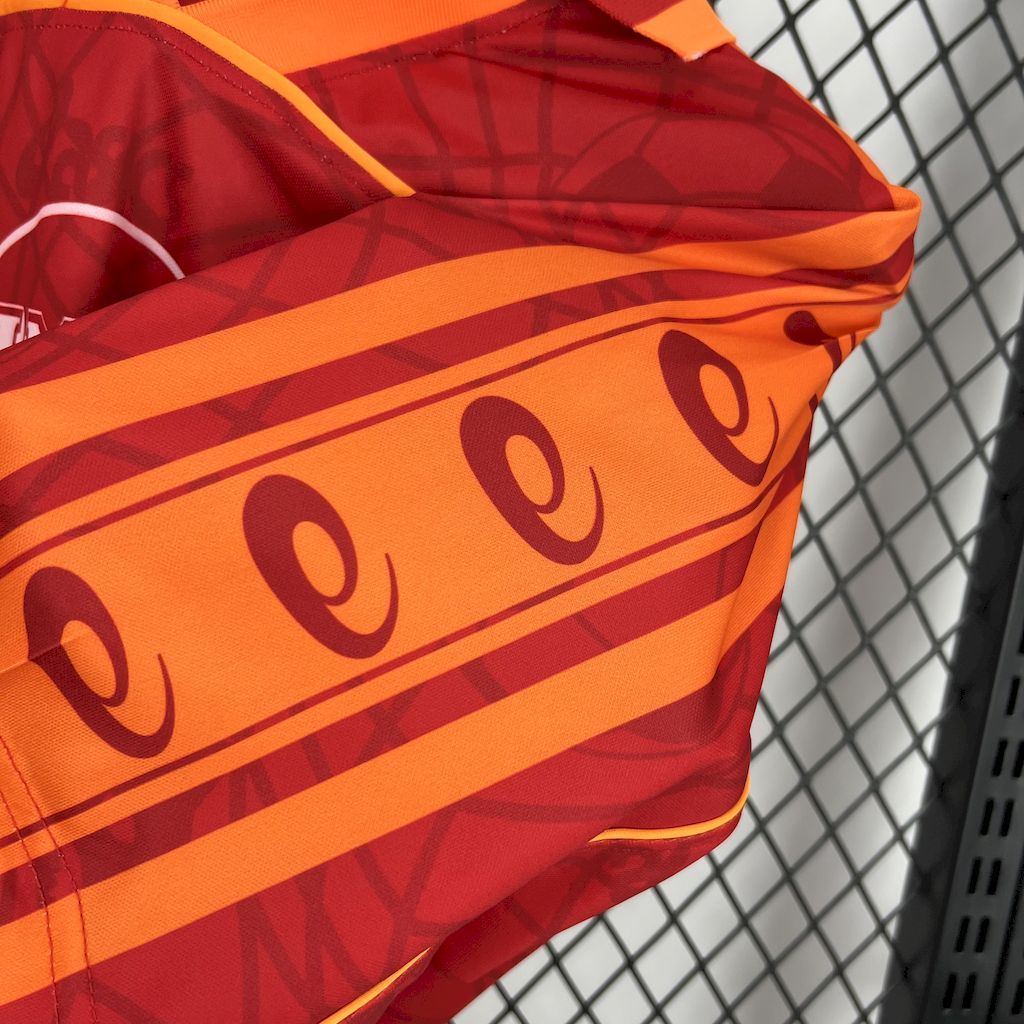 Red jersey with orange shoulder stripe and soccer-ball pattern detail.