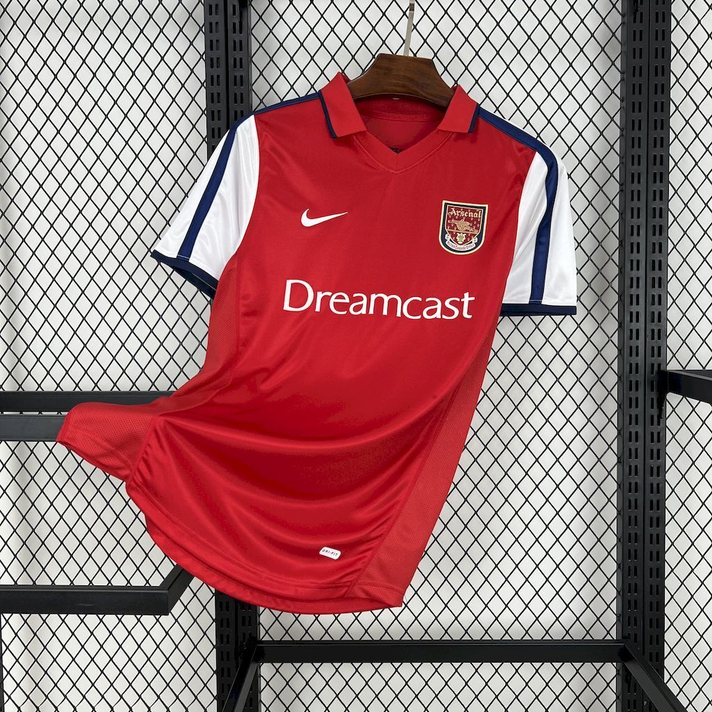 Red retro soccer jersey with white shoulder stripes, Arsenal crest, and Dreamcast sponsor