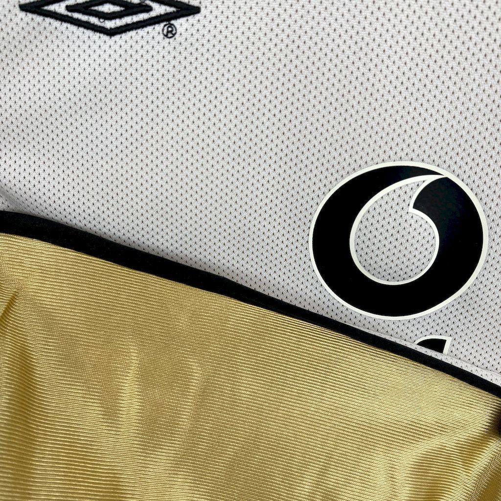 D logo badge detail and gold trim on white textured football jersey fabric