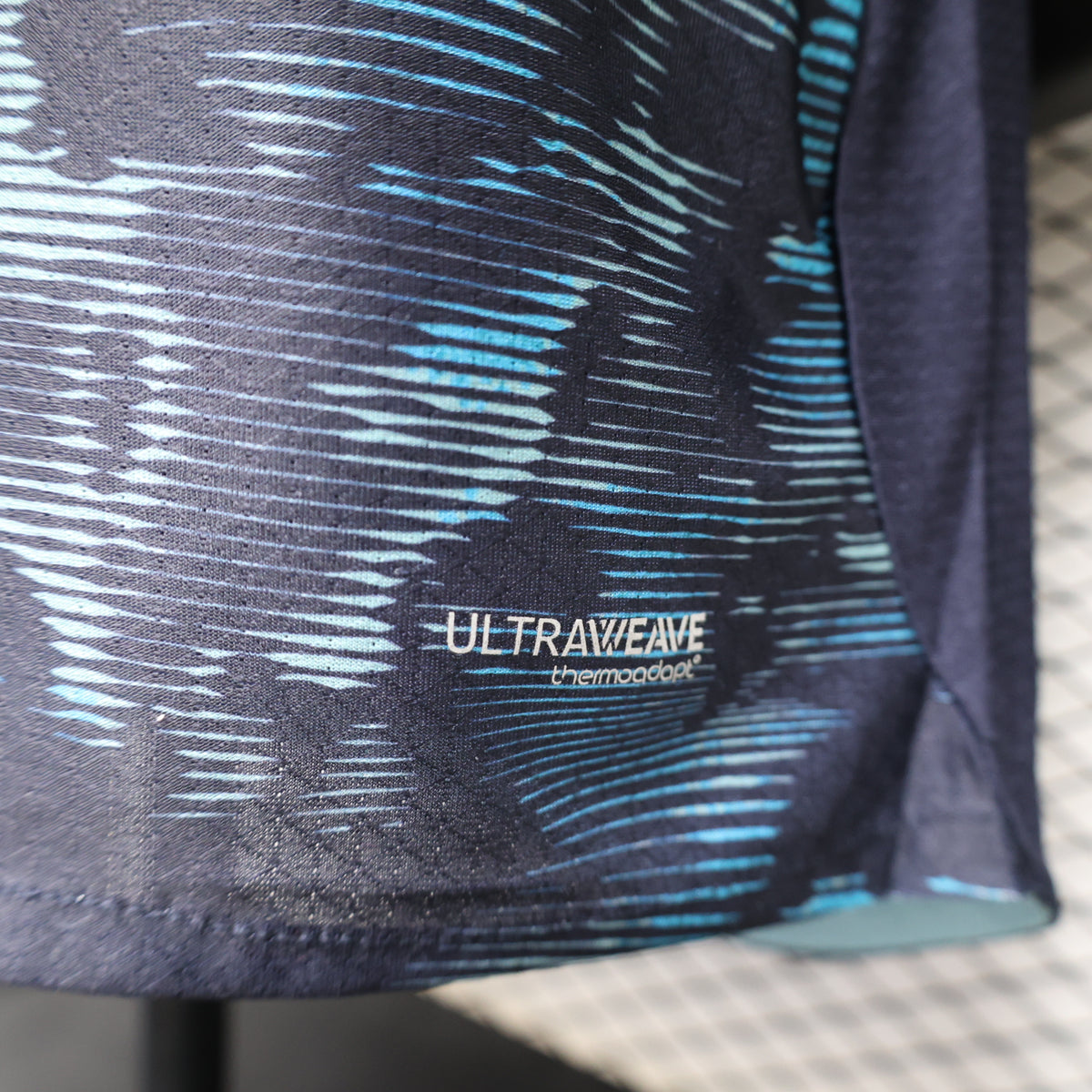 Close-up of ULTRAWAVE text on navy-and-blue abstract camo jersey sleeve
