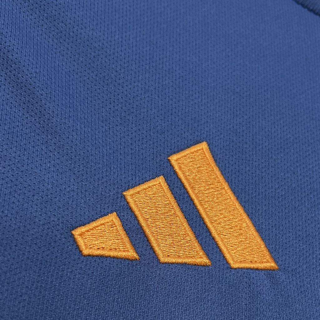Close-up of gold adidas logo stitching on blue soccer jersey