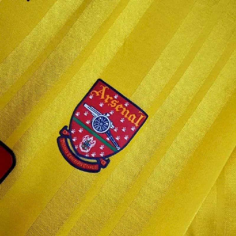 Yellow retro jersey sleeve patch with Arsenal crest on maroon background and white text