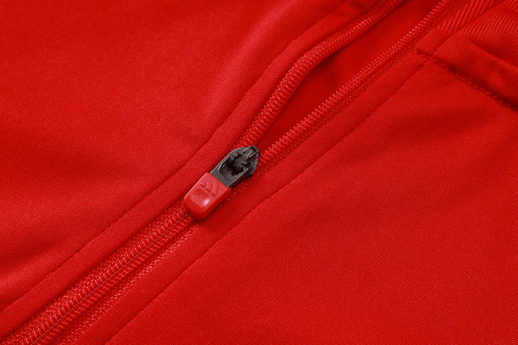Red pant zipper and pocket opening with black pull tab on the front seam.