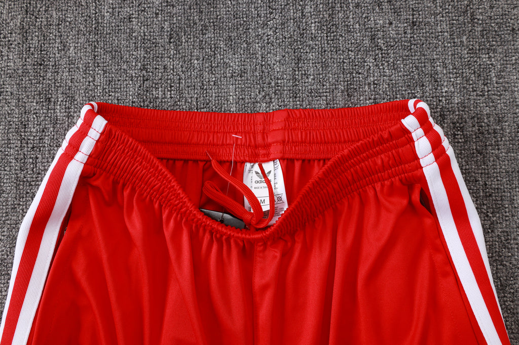 Red track pants with elastic waistband, drawstring, and white stripe bands at the sides.