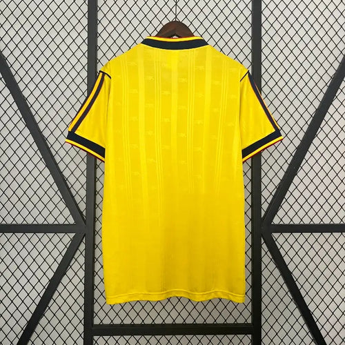 Yellow soccer jersey back view with black collar trim and side stripe accents