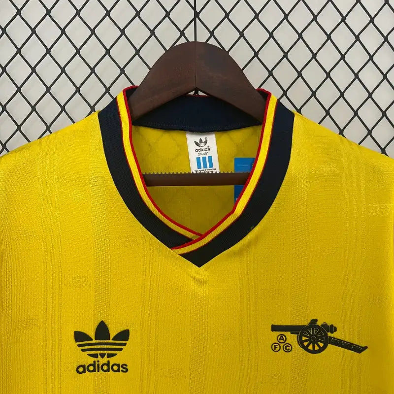 Yellow soccer jersey close-up: black V-neck collar, adidas logo, patch details