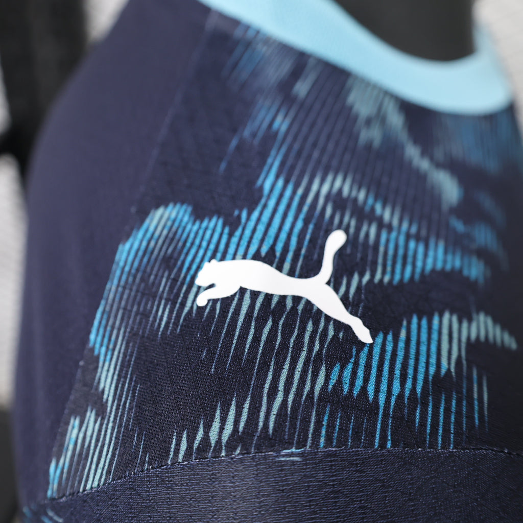 Close-up of white Puma cat logo on navy-and-blue camo jersey fabric