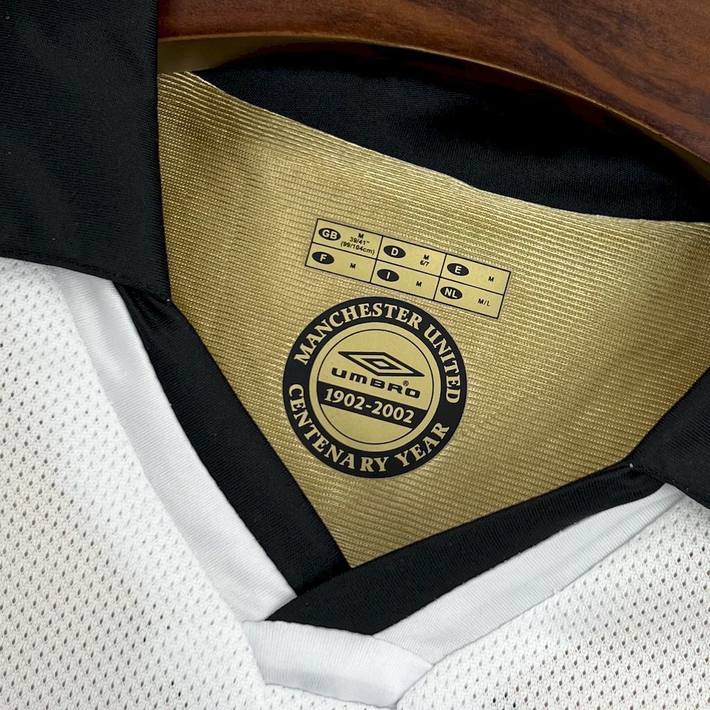 Gold Centenary Year 1902–2002 patch on black collar of white football jersey