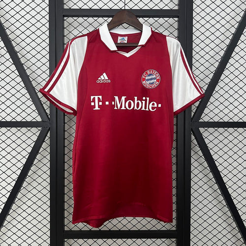 Red Bayern Munich home jersey on hanger with Adidas logo, T-Mobile print, crest