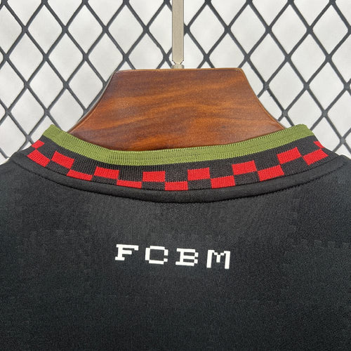 Black jersey collar with red-and-black check trim, green edge, and “FCBM” chest print.