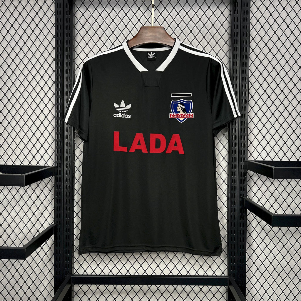 Black Colo-Colo away soccer jersey with adidas stripes, crest, and red 'LADA' sponsor