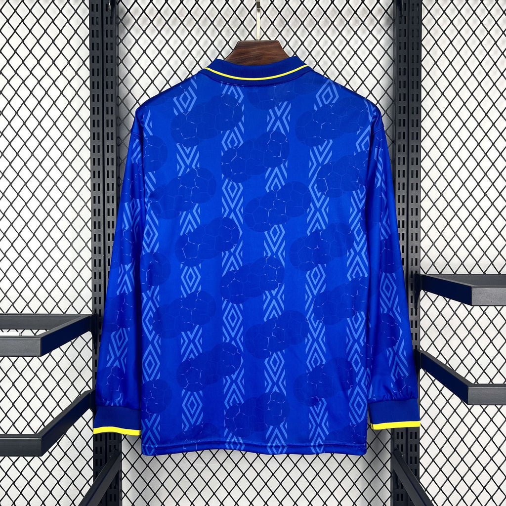 Blue long-sleeve soccer jersey, geometric pattern all over, yellow-trim cuffs and collar