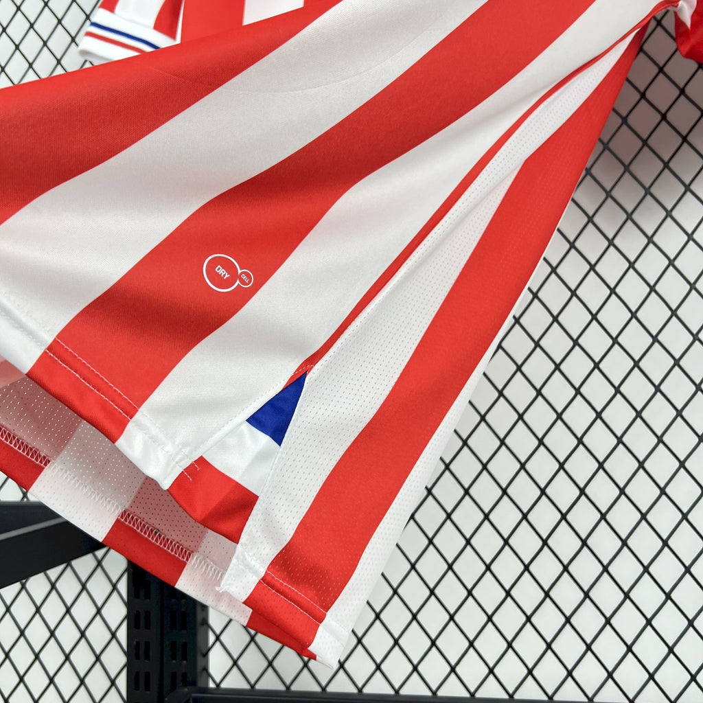 Retro soccer jersey sleeve close-up with red-and-white stripes and small blue icon.