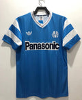 Blue retro soccer jersey with white stripes, V-neck, and Panasonic front sponsor logo