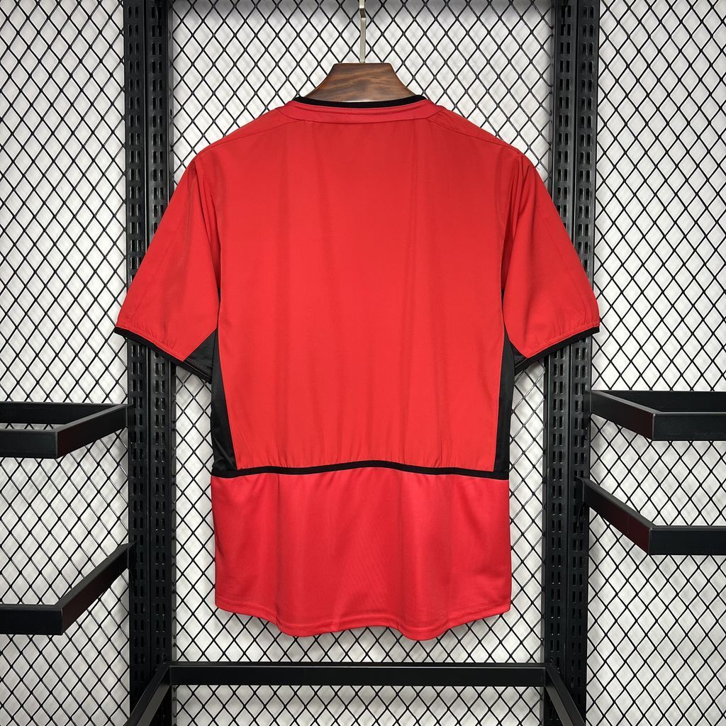 Red Manchester United home football shirt with black trim and back panel view