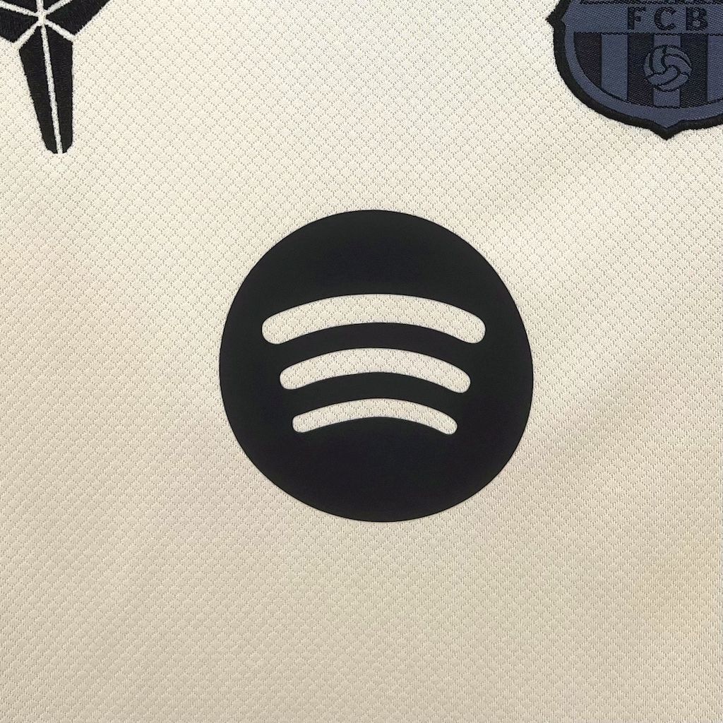 Cream kid jersey with large black circular sponsor logo