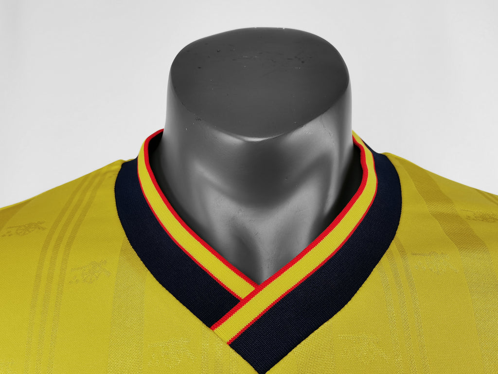 Yellow football jersey collar close-up: navy V-neck with red-and-yellow striped trim